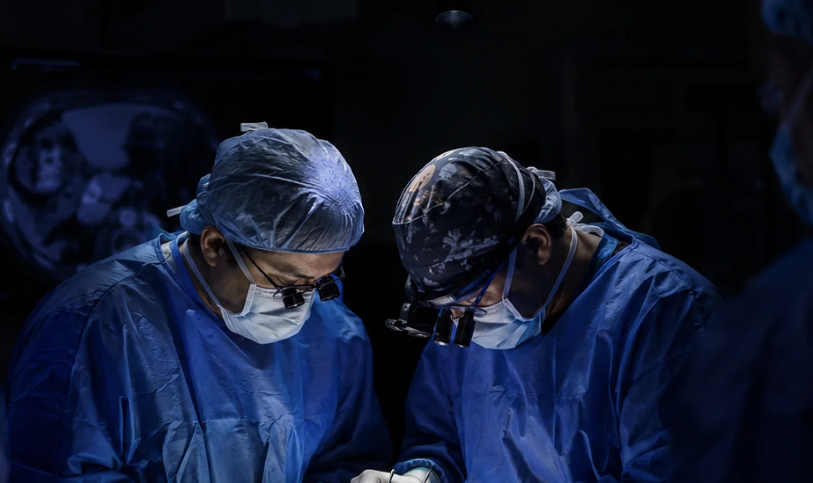 Dois cirurgiões operando lado a lado durante procedimento oncológico